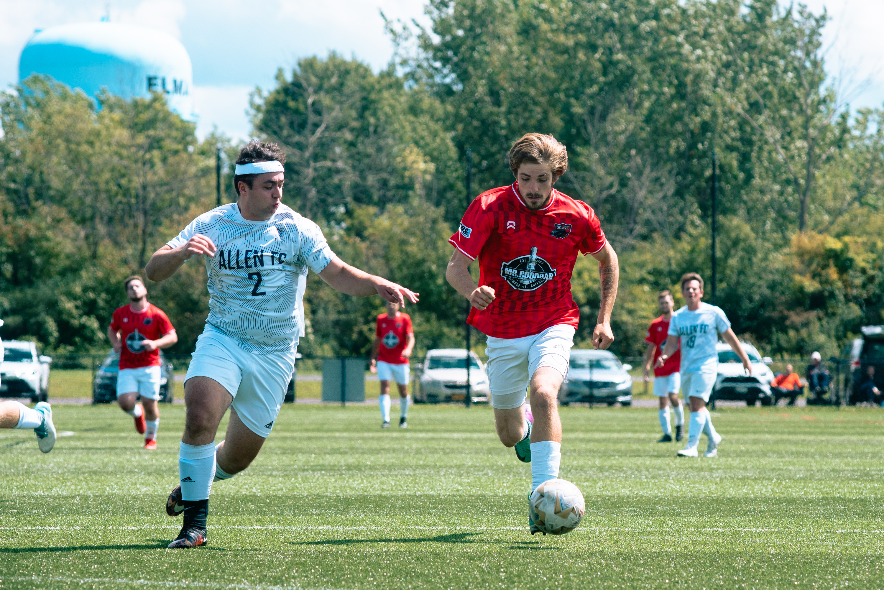 Rust Belt United midfielder bringing down a high ball under pressure near the sideline